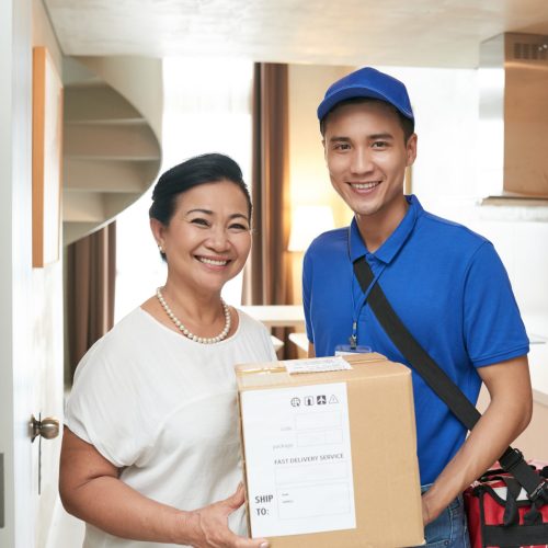 Happy senior woman and courier with big parcel